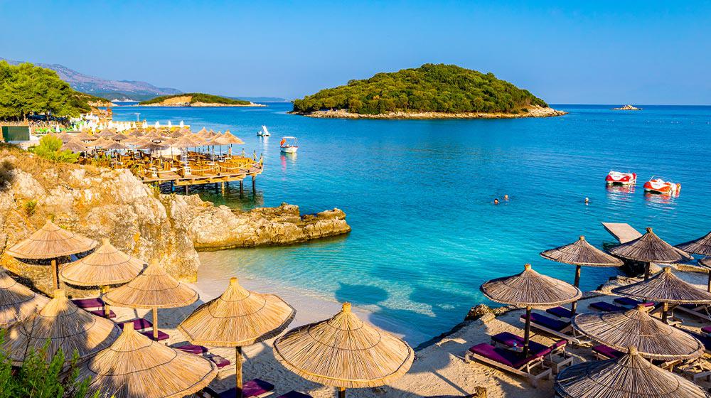 Strand mit Sonnenschirmen und Sonnenliegen an der Albanischen Riviera