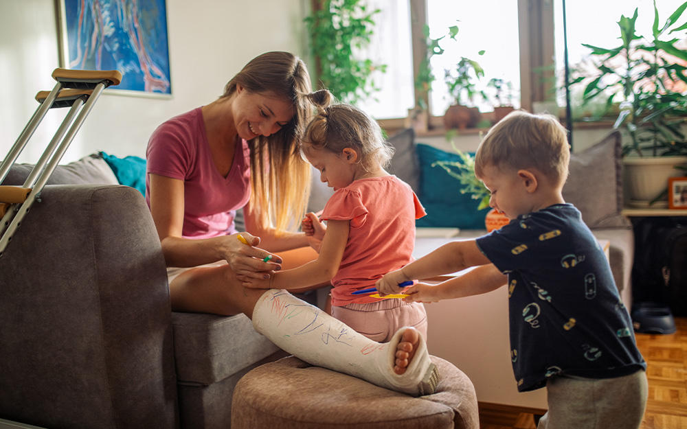 Mutter mit eingegipstem Bein verbringt Urlaub nach Reisestorno mit ihren Kindern zuhause.